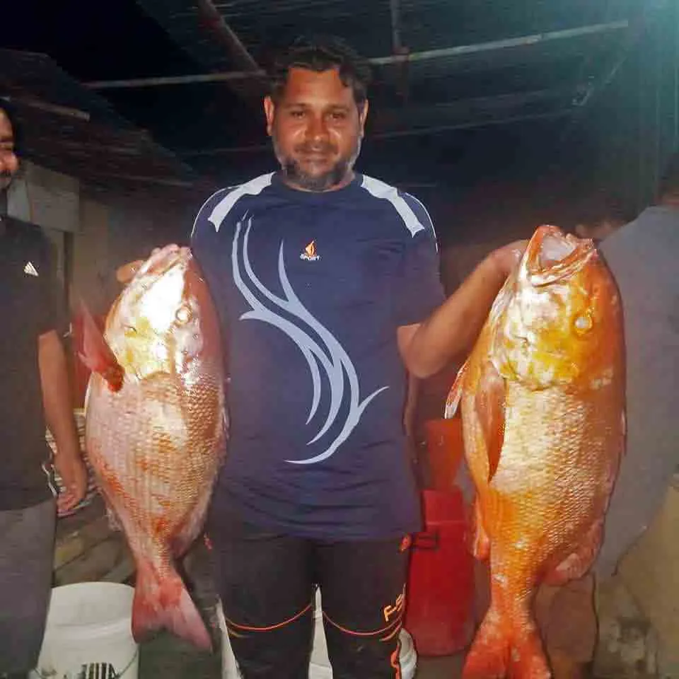 Niyaz proudly displaying two large two-spot red snappers caught during an evening fishing session in the Male'.